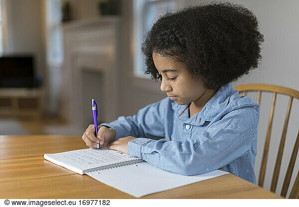 Ten year-old bi-racial girl doing homework at table