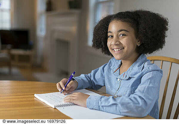 Ten year-old bi-racial girl doing homework at table
