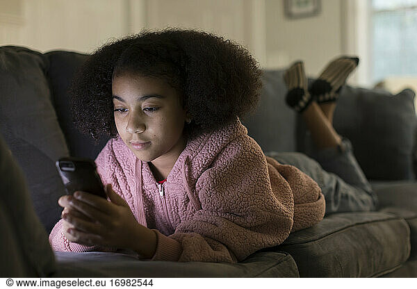 Ten year-old bi-racial girl looking at her cell phone while l