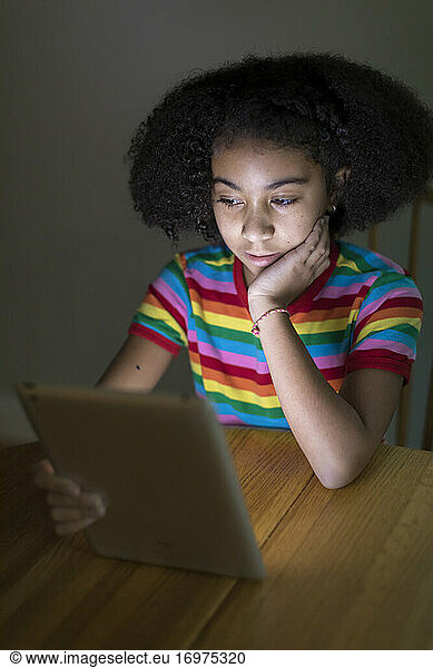 ten year-old bi-racial girl looking at ipad at table