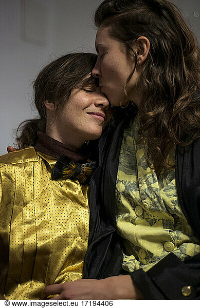 Tender moment between two gay women in love at home cuddling