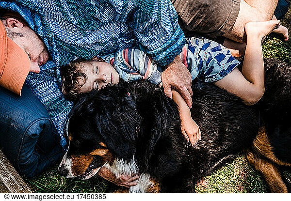 Tender moment with father and son napping with family dog