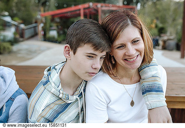 Tender teen son in blue striped shirt hugging smiling mom