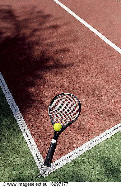 Tennis ball with racket on floor in sports court