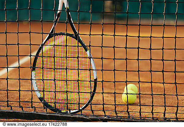 Tennis racket and ball by net at at sports court