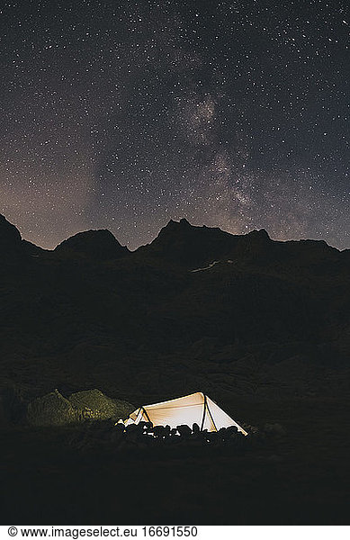 Tent at night agains the Milky Way over the mountains Sierra de Gredos