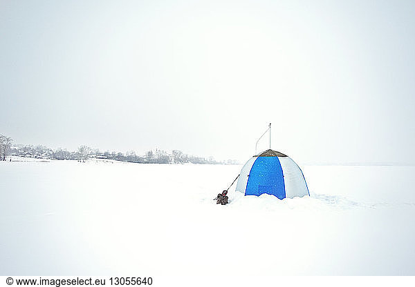Tent on snow covered field against clear sky