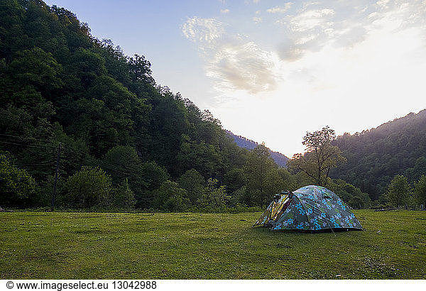 Tent setup on grassy field by mountain against sky
