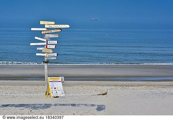 Texel  Netherlands  August 2019: Big signpost with many signs with various leisure activities written on them in Dutch on beach Paal 9 on island Texel with blue sea and sky in background