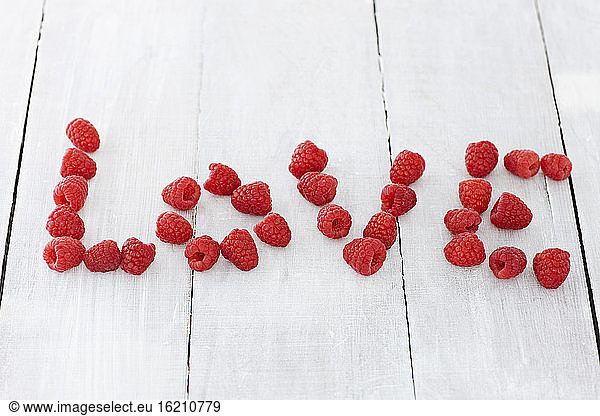 Text formed with raspberries on wooden table  close up