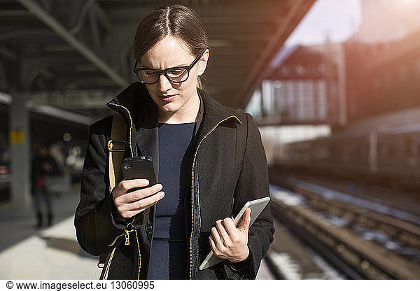 Textnachrichten einer Geschäftsfrau im Stehen am Bahnhof