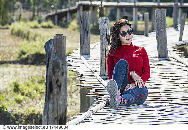 Thai woman sitting on traditional bamboo boardwalk in north Thailand