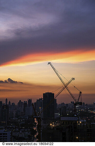 Thailand  Bangkok  Clouds over city downtown at dusk with industrial cranes in background