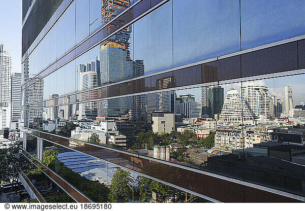 Thailand  Bangkok  Skyscrapers reflecting in glass wall