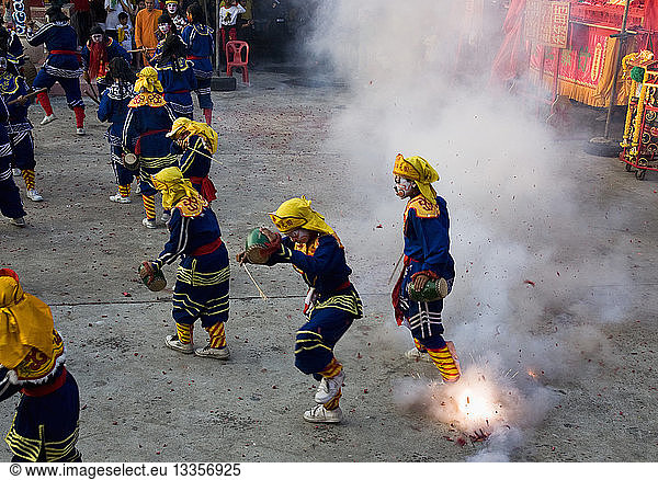 Thailand  Bangkok  Thai boys in Chinese character costume dancing and drumming with firecrackers exploding at local temple.