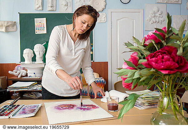 The artist works in her studio  paints a peonies