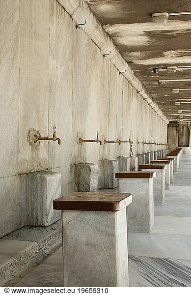 The Blue Mosque  Istanbul  a row of marble seats and taps for the worshippers to wash their feet  marble drain channel and floors.