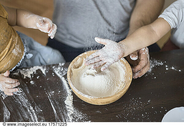 The boy catches the sifted flour with his hand