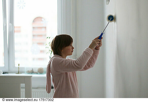 The child paints the wall in the room.
