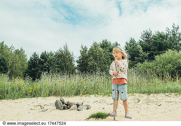 The cute girl spending time on the shore of the beautiful lake.