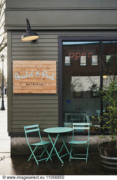The exterior of a small business  street view  of a coffee shop with table and chairs outside.