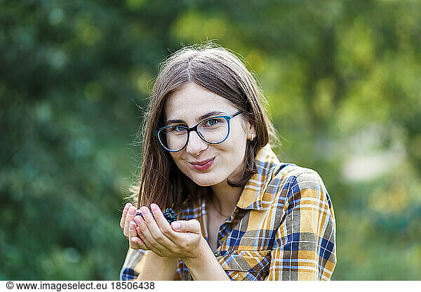 The farmer girl eating the blackberry with satisfaction on green farm