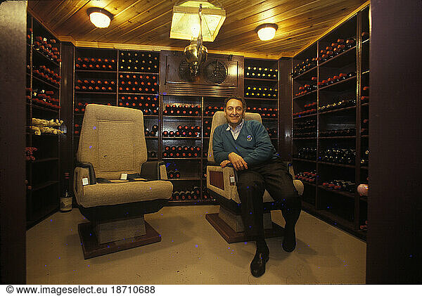 The former chairman of a large financial company smiles for a portrait in the wine cellar of his home in Connecticut.