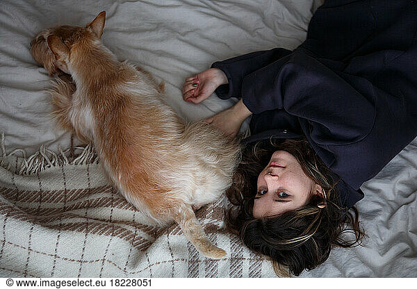 The girl and the dog lie on the bed. top view