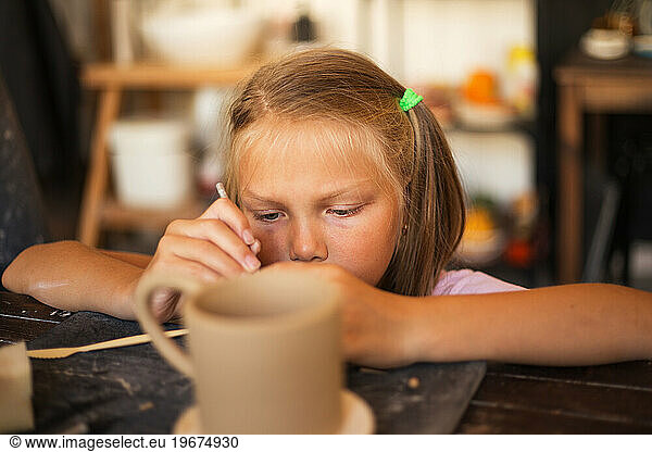The girl works with ceramic clay in modern pottery workshop. Hob