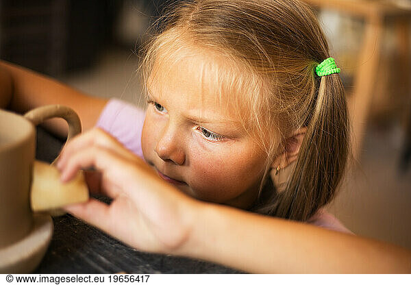 The girl works with ceramic clay in pottery studio  close up. Ho