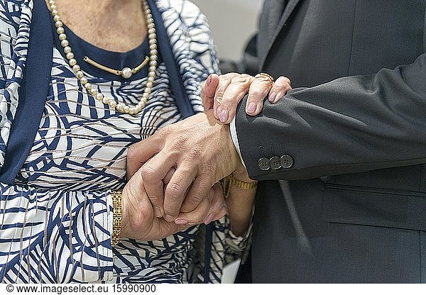 The groom holds his grandmother's hands lovingly on the wedding day