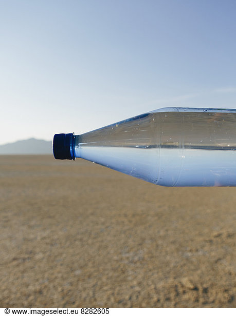 The Landscape Of The Black Rock Desert In Nevada. A Bottle Of Water. Filtered Mineral Water. Sideways. The Water Level Matching The Horizon.