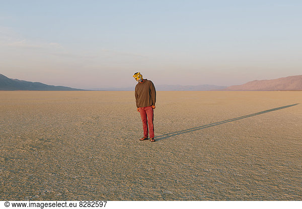 The Landscape Of The Black Rock Desert In Nevada. A Man Wearing An Animal Mask. Casting A Long Shadow On The Ground.