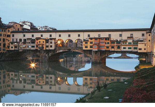 The medieval Ponte Vecchio over the Arno River in the centre of Florence city. Buildings reflected in the water.