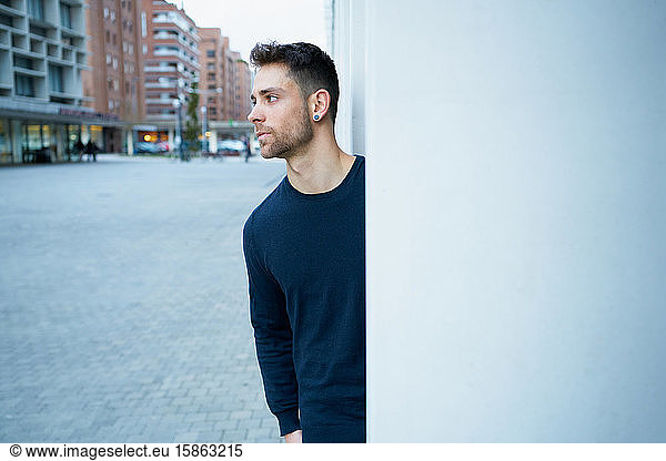 the modern man in casual clothes leaning against a wall
