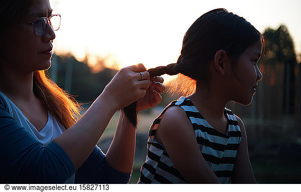 The mother styling her daughter's hair during the sunset