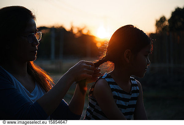 The mother styling her daughter's hair during the sunset