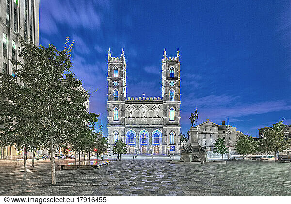 The Notre Dame Basilica  light up at dusk in the city square in the Old Town of Montreal.