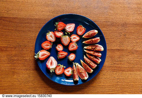 The plate of fresh tasty slices of fruits such as strawberry and fig