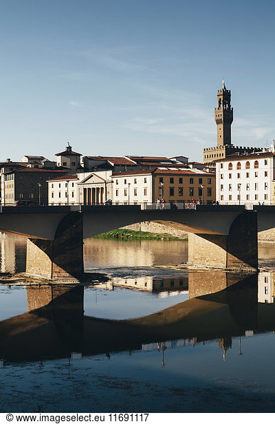 The Ponte alle Grazie  historic bridge over the flat calm water of the River Arno  in the middle of Florence.