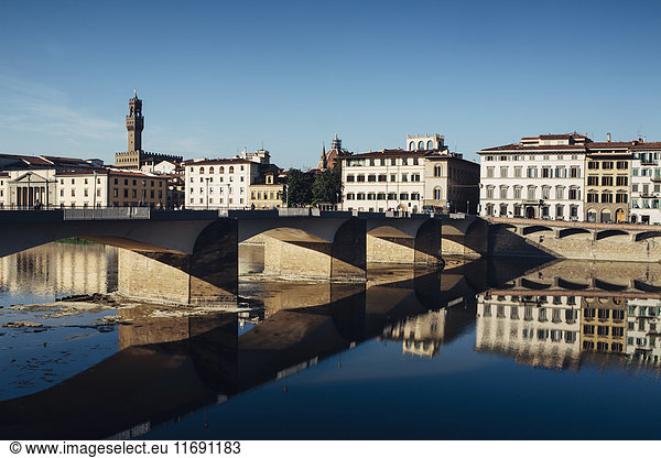 The Ponte alle Grazie  historic bridge over the flat calm water of the River Arno  in the middle of Florence.