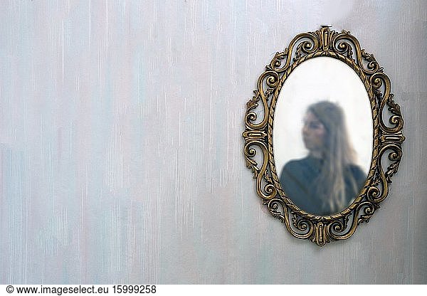 The reflection of a woman in a antique golden mirror in the vintage interior  old pattern wallpaper background space for text.