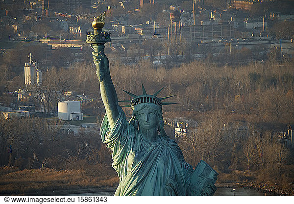 The Statue of Liberty in front of New Jersey industrial suburbs  NYC.
