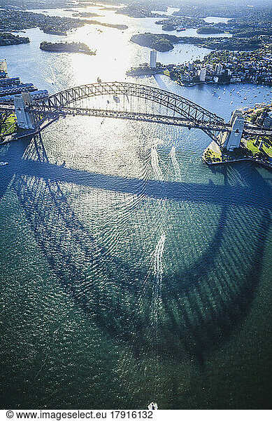 The Sydney Harbour Bridge  the shadow of the arch on the water  and aerial view of the landscape.