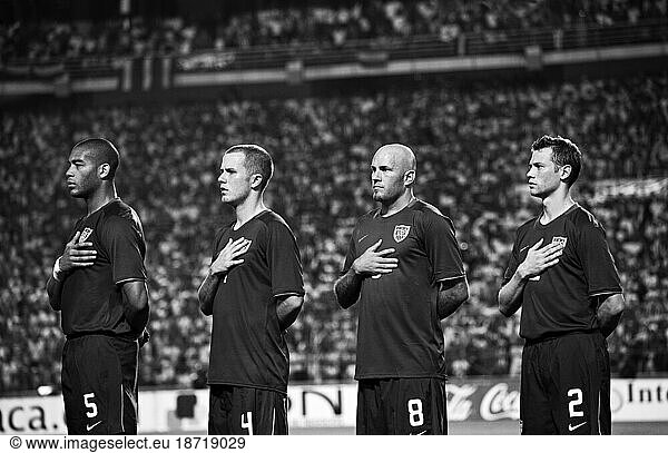 The US soccer team listens to the National Anthem before the game begins.