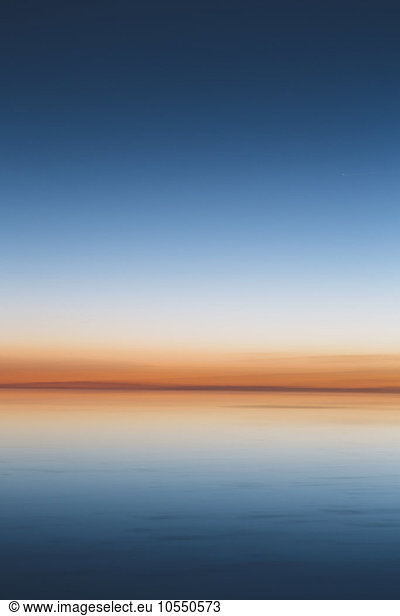 The view to the clear line of the horizon where land meets sky  across the flooded surface of Bonneville Salt Flats. Dawn light