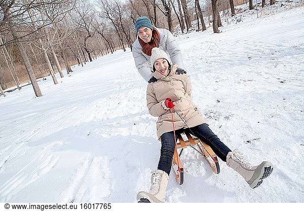 The young couple sledding in the snow