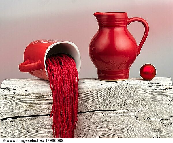 Thema Lustig  Verschieden  Neuartig  Rot  weiß  Stillleben mit roten Keramik-Kannen  Wollfäden und roter Kugel  Studioaufnahme  Symbolfoto