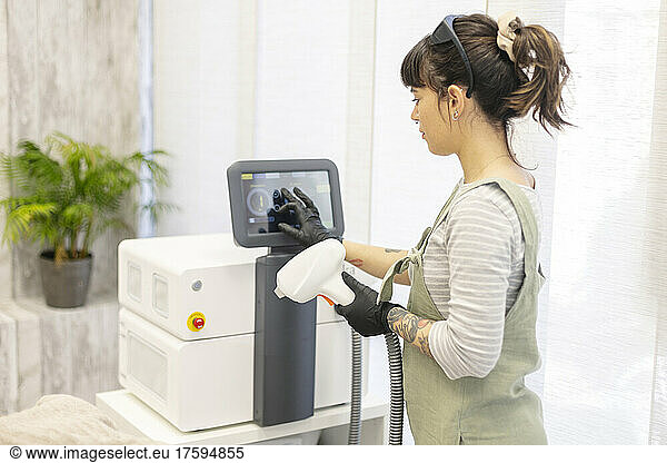 Therapist checking laser hair removal machine at aesthetic clinic