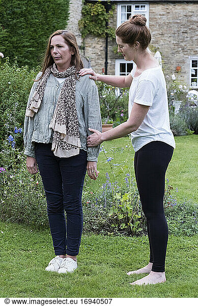 Therapist focussing on the standing posture of a client in a garden.